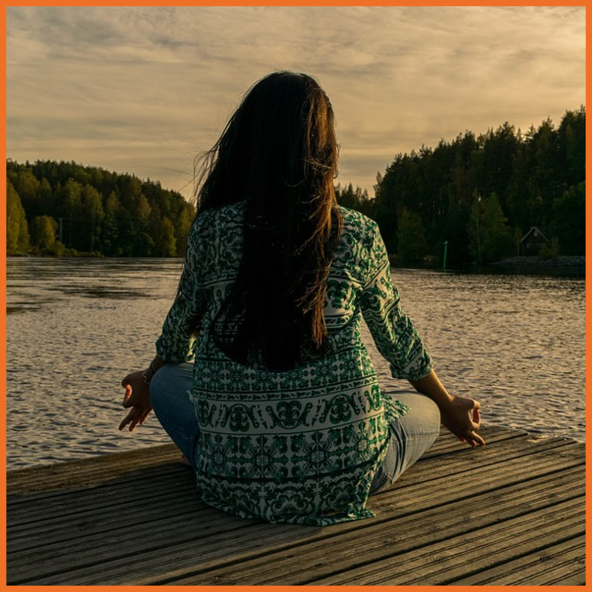 Billede af en kvinde, der laver yoga ved en sø.
