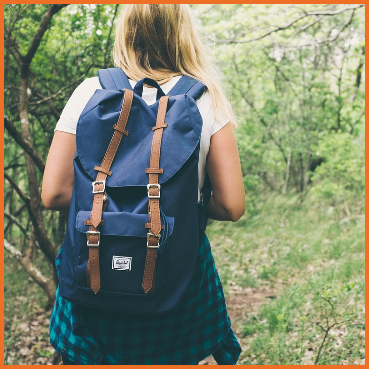Pige der går med en rygsæk i en skov.