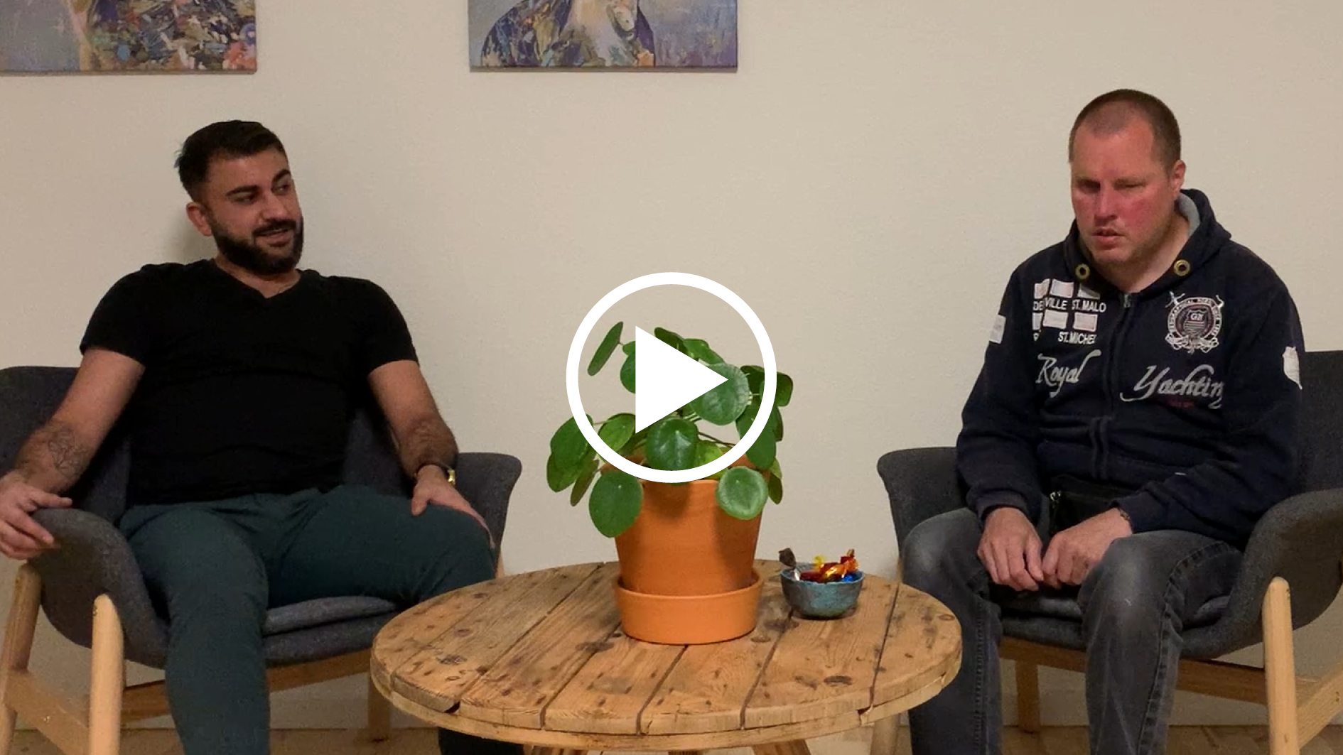 Foto af Frank og Rime. Der er et ikon af en afspiller på midten af billedet.